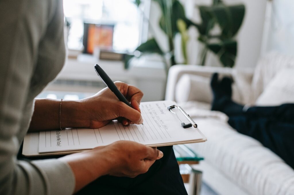 Mother writing her child's behaviour symptoms from the ASD behaviour trait checker list.