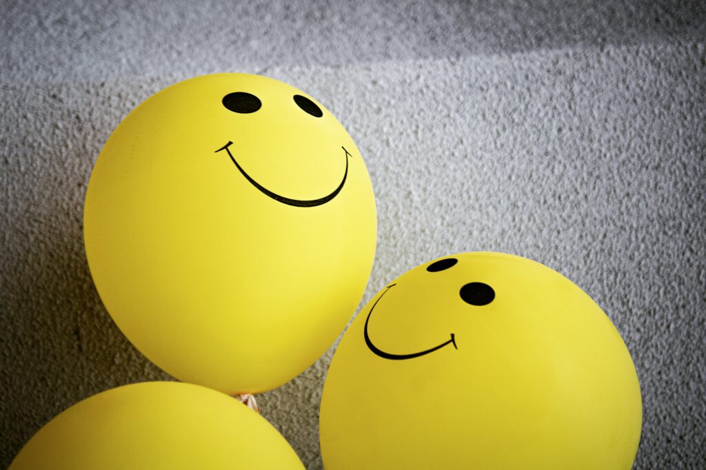 Two yellow balloons with smiley faces drawn on them, symbolizing positive reinforcement.