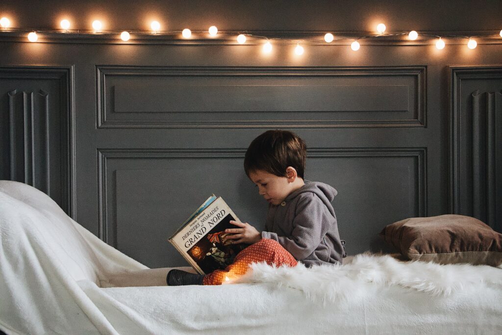 A little boy is reading his book in bed before sleeping.